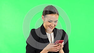 Young smiling woman texting on her phone and rejoice. Green screen