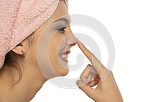 Young smiling woman with towel on her head,  touches her nose