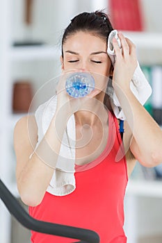 young smiling woman with towel and water after training