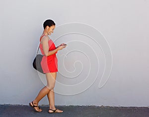 Young smiling woman walking with mobile phone and earphones