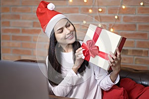 Young smiling woman wearing red Santa Claus hat making video call on social network with family and friends on Christmas day