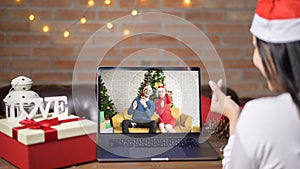Young smiling woman wearing red Santa Claus hat making video call on social network with family and friends on Christmas day