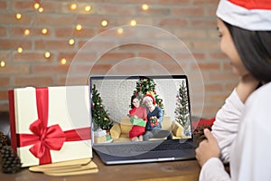 Young smiling woman wearing red Santa Claus hat making video call on social network with family and friends on Christmas day