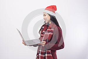 Young smiling woman wearing red Santa Claus hat making video call on social network with family and friends on white background