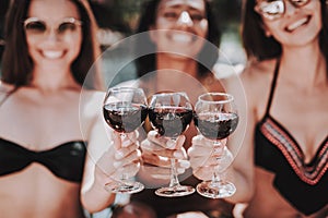 Young Smiling Women Drinking Wine at Poolside