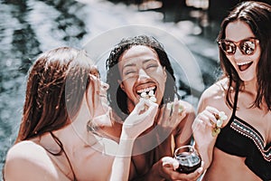 Young Smiling Women Drinking Wine at Poolside