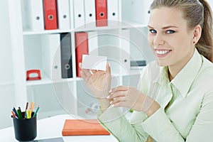 Young smilling secretary showing empty blank paper card sign with copy space for text.