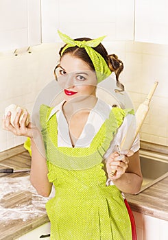 Young smilng housewife cooking dough for baking