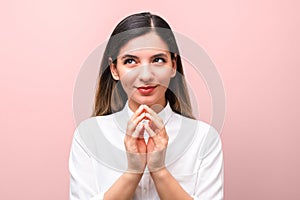 Young sneaky woman, scheming something for april first, fools day against pink background