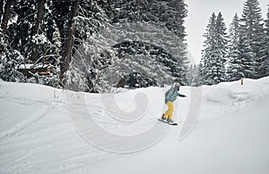 Young snowboarder snowboarding in mountain