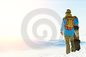 Young snowboarder standing next to snowboard thrusted into snow and enjoying sun-set