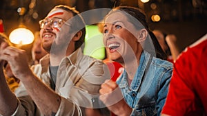 Young Soccer Fans Couple Watching a Live Football Match in a Sports Bar. Crowd with Colored Faces