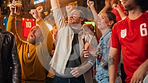 Young Soccer Fans Couple Watching a Live Football Match in a Sports Bar. Crowd with Colored Faces