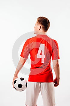 Young soccer player with ball on black background in studio.