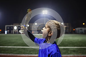 Young soccer player in blue jersey with ten number holding a winners cup after the winning goal