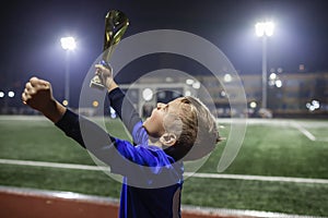 Young soccer player in blue jersey with ten number holding a winners cup after the winning goal