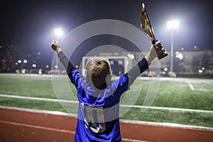 Young soccer player in blue jersey with ten number holding a winners cup after the winning goal