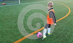 Young Soccer Player Kicking Ball on Soccer Pitch. Boy in Sports Clothing Playing Football. Child Training Soccer with Soccer
