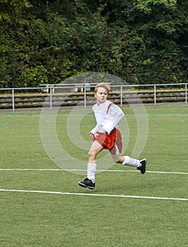 Young soccer player runs over the football ground