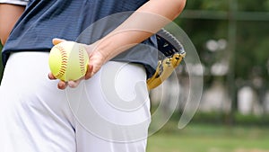 A young Softball player ready to peatch from his position in the outfield.holding a Softball ball in his hands while playing catch