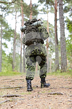 Young soldier with backpack in forest