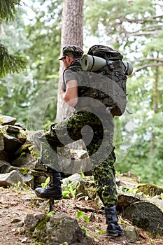 Young soldier with backpack in forest
