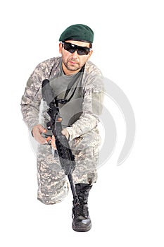 Young soldier with beret and glasses holding an automatic gun