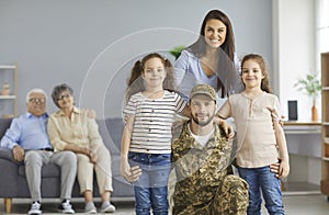 Portrait of happy young soldier together with his family upon returning back home