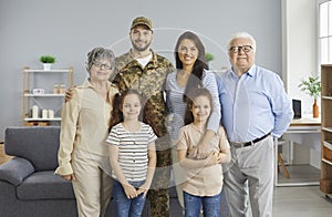 Portrait of happy young soldier and his family standing in the living-room together