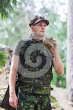 Young soldier with gun and flask in forest