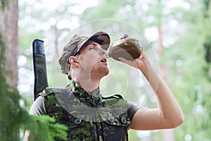 Young soldier with gun and flask in forest