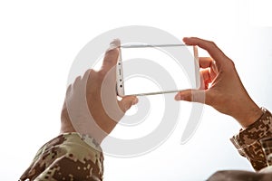 Mladý vojak držanie mobilný telefón prázdny obrazovka na bielom 