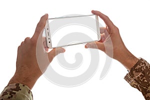 Young soldier holding a mobile phone with blank screen on white background