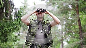 Young soldier or hunter with binocular in forest