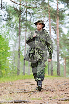 Young soldier or hunter with gun in forest