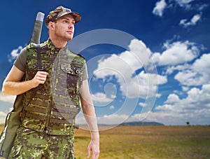 Young soldier or hunter with gun over savannah