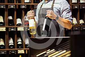 Young sommelier holding bottle of red wine in cellar