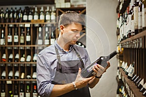 Young sommelier holding bottle of red wine in cellar