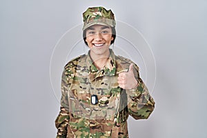 Young south asian woman wearing camouflage army uniform doing happy thumbs up gesture with hand