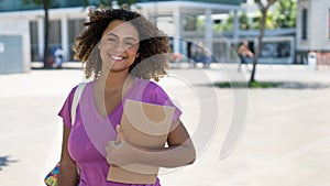 Young spanish female student with backpack infront of university