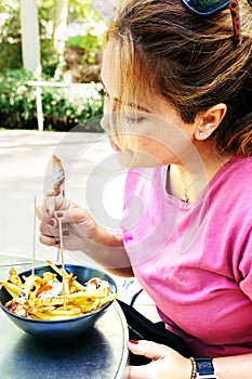 A young Spanish woman eating anchovies and chips on the terrace of a bar. Spanish tapas concept