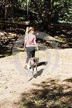 Young Spanish woman walking in a park with her rescued greyhound dog