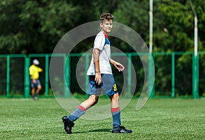 Young sport boys in white sportswear running and kicking a ball on pitch. Soccer youth team plays football in summer.