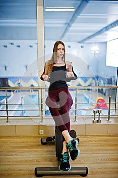 Young sport girl workout in gym. Fitness woman doing exercises on stationary bicycle