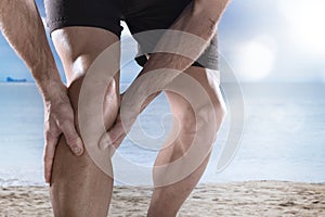 Young sport man with athletic legs holding knee in pain suffering muscle injury running