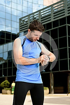 Young sport man checking time on chrono timer runners watch holding water bottle after training session