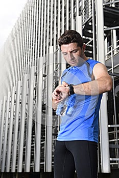 Young sport man checking time on chrono timer runners watch holding water bottle after training session photo