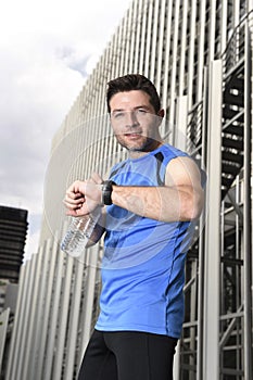 Young sport man checking time on chrono timer runners watch holding water bottle after training session photo