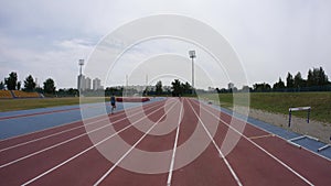 A young sport man is running at the city athletics stadium during a day training in slow motion 4K video on UHD wide