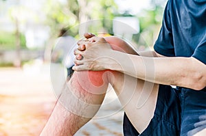 Young sport man with strong athletic legs holding knee